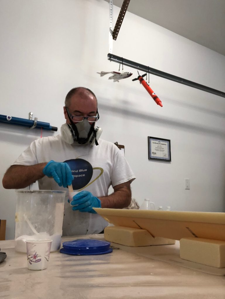 Man with breathing filter mixing epoxy in workshop